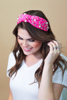 a twisted center knot headband with varying sizes of pearl and rhinestone detailing in pink