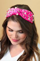 a twisted center knot headband with varying sizes of pearl and rhinestone detailing in pink