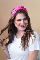 a twisted center knot headband with varying sizes of pearl and rhinestone detailing in pink
