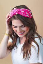 a twisted center knot headband with varying sizes of pearl and rhinestone detailing in pink