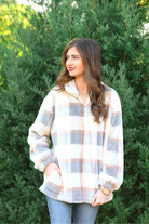 a taupe long-sleeve pullover with a neutral plaid pattern, a quarter zip, a foldable collar, and pockets made of a super soft material