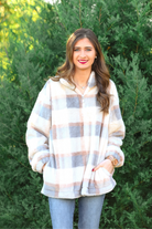 a taupe long-sleeve pullover with a neutral plaid pattern, a quarter zip, a foldable collar, and pockets made of a super soft material