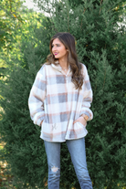 a taupe long-sleeve pullover with a neutral plaid pattern, a quarter zip, a foldable collar, and pockets made of a super soft material