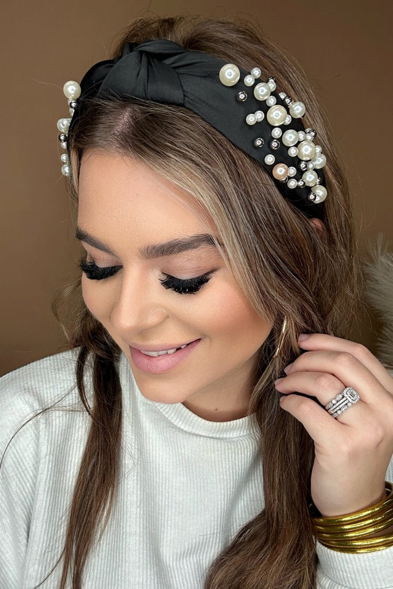 a twisted center knot headband with varying sizes of pearl detailing in black