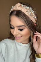 a twisted center knot headband with varying sizes of pearl detailing in champagne