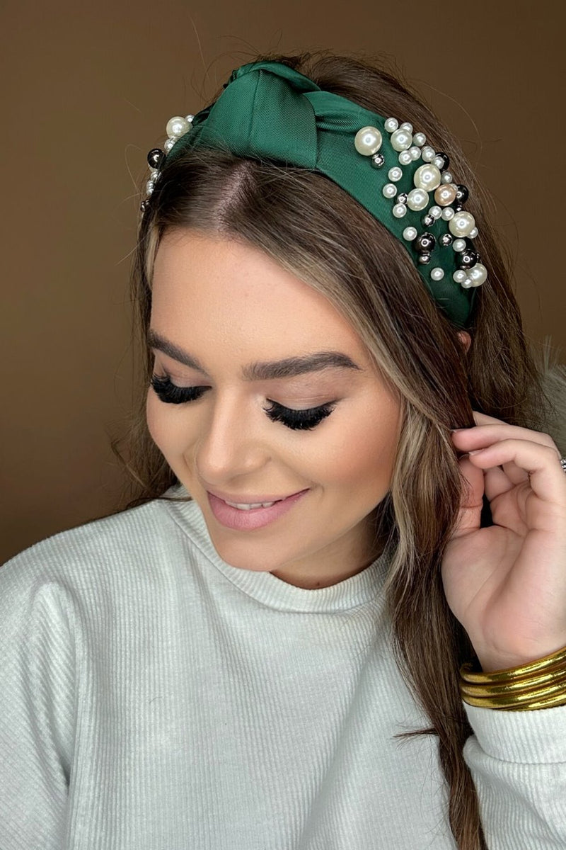 a twisted center knot headband with varying sizes of pearl detailing in green