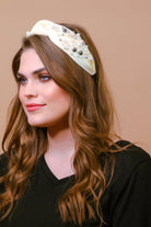 a twisted center knot headband with varying sizes of pearl detailing in ivory