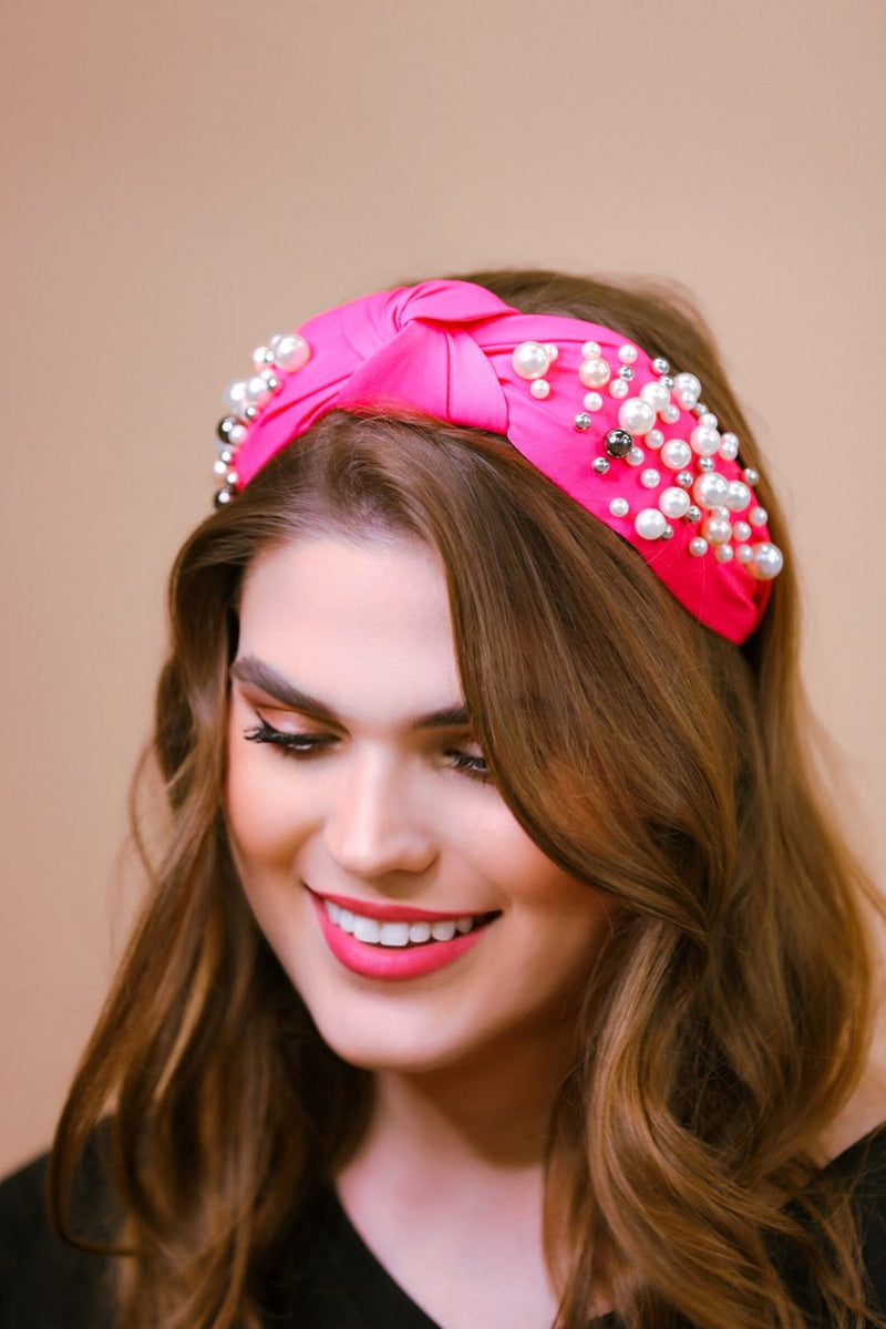 a twisted center knot headband with varying sizes of pearl detailing in pink