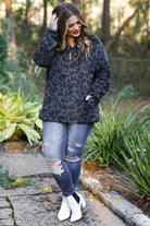 a long-sleeve fluffy pullover with a quarter zip, convenient pockets, and a foldable collar on a black leopard sherpa fabric