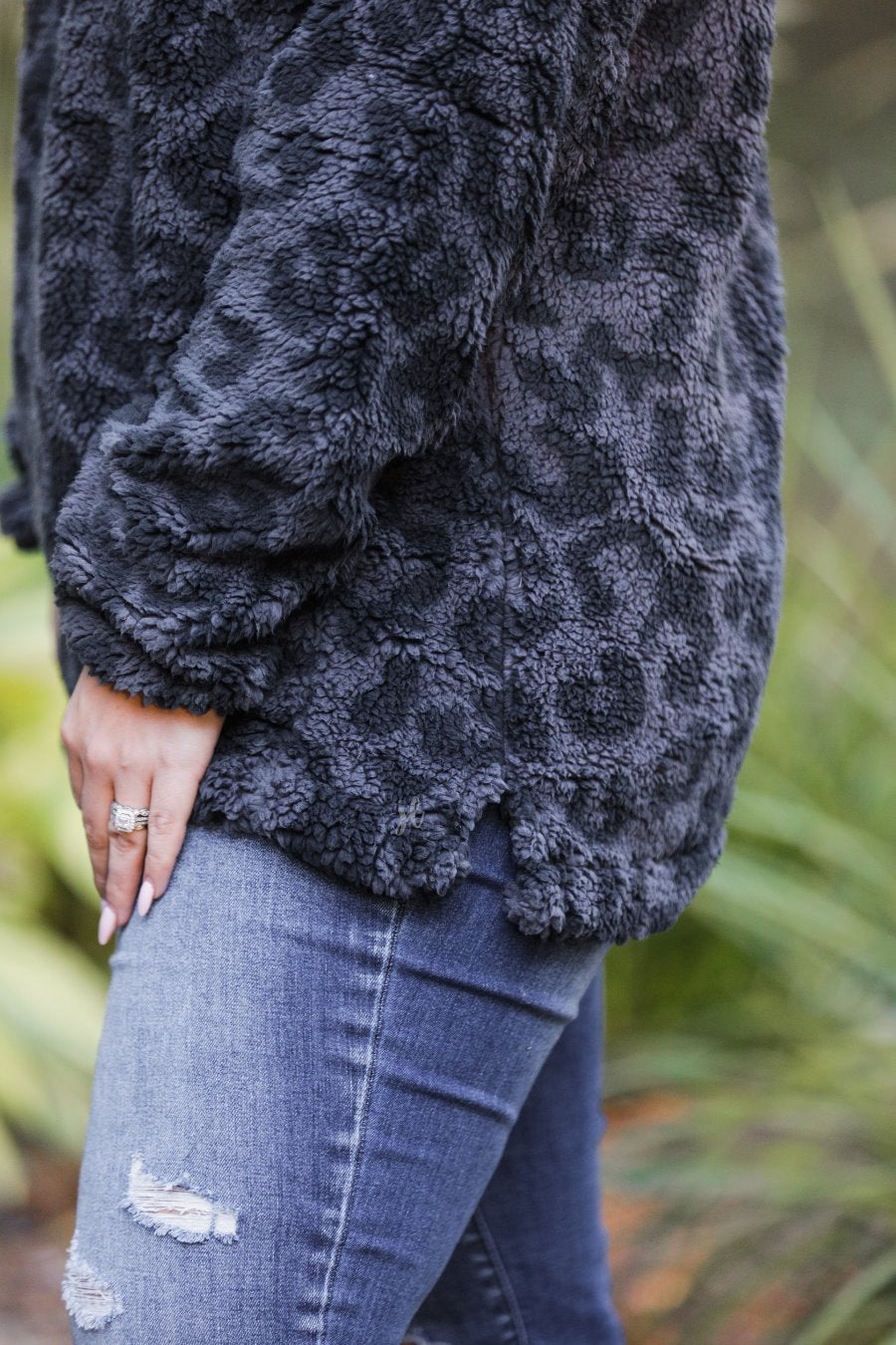 a long-sleeve fluffy pullover with a quarter zip, convenient pockets, and a foldable collar on a black leopard sherpa fabric