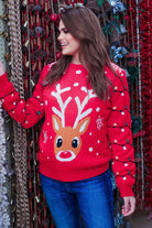 a red long-sleeve heavy sweater made of soft, cozy material with a cheerful reindeer graphic framed by delicate snowflakes, playful snowflake accents, and whimsical multicolor light strands wrapping around the sleeves