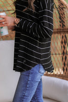 lightweight horizontal striped top with long sleeves, a crew neckline, and a slouched silhouette that ends in a rounded hemline on a solid black base