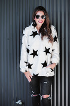 a long-sleeve fluffy pullover with a quarter zip, convenient front pockets, and a foldable collar on a white fabric with a black star pattern