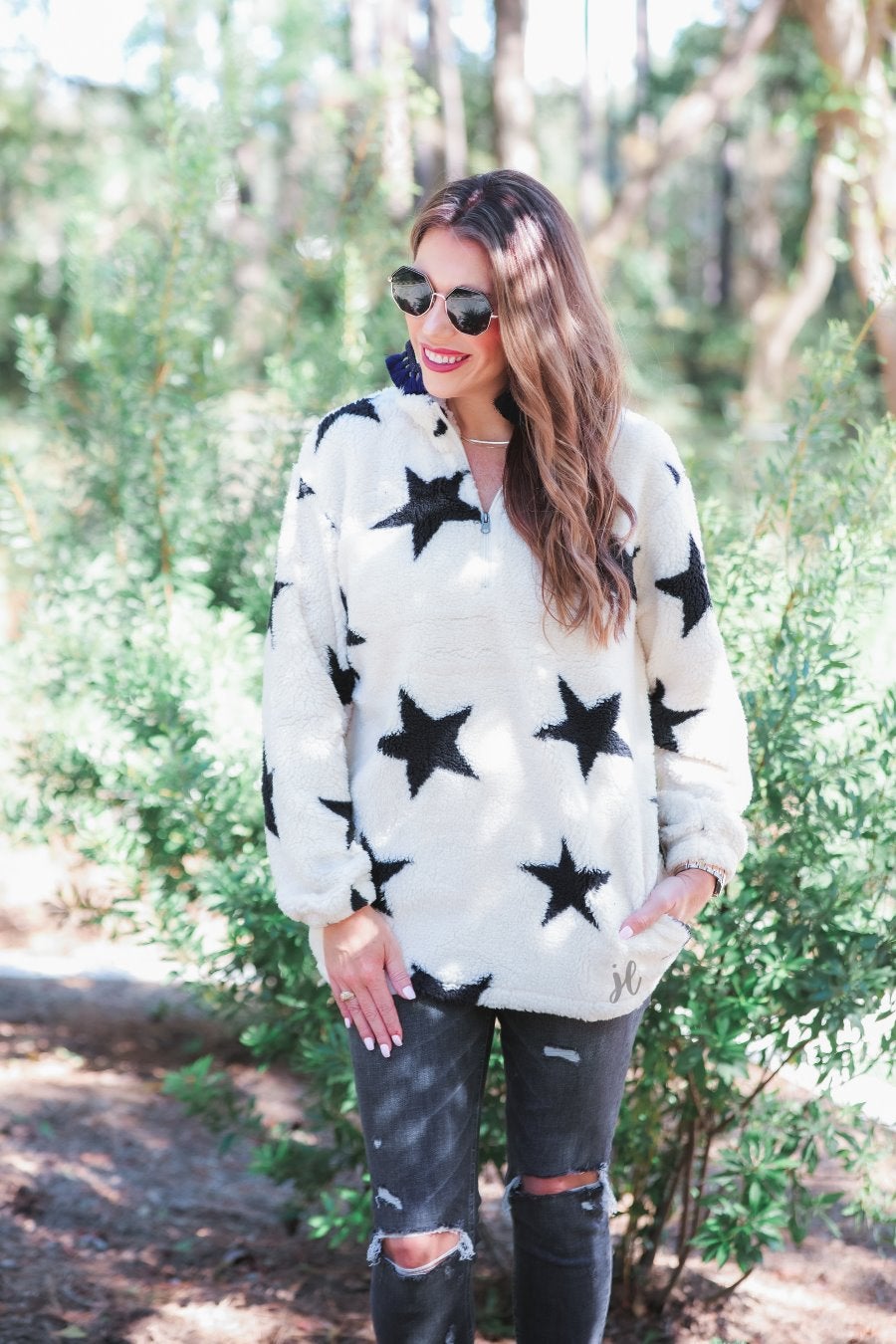 a long-sleeve fluffy pullover with a quarter zip, convenient front pockets, and a foldable collar on a white fabric with a black star pattern