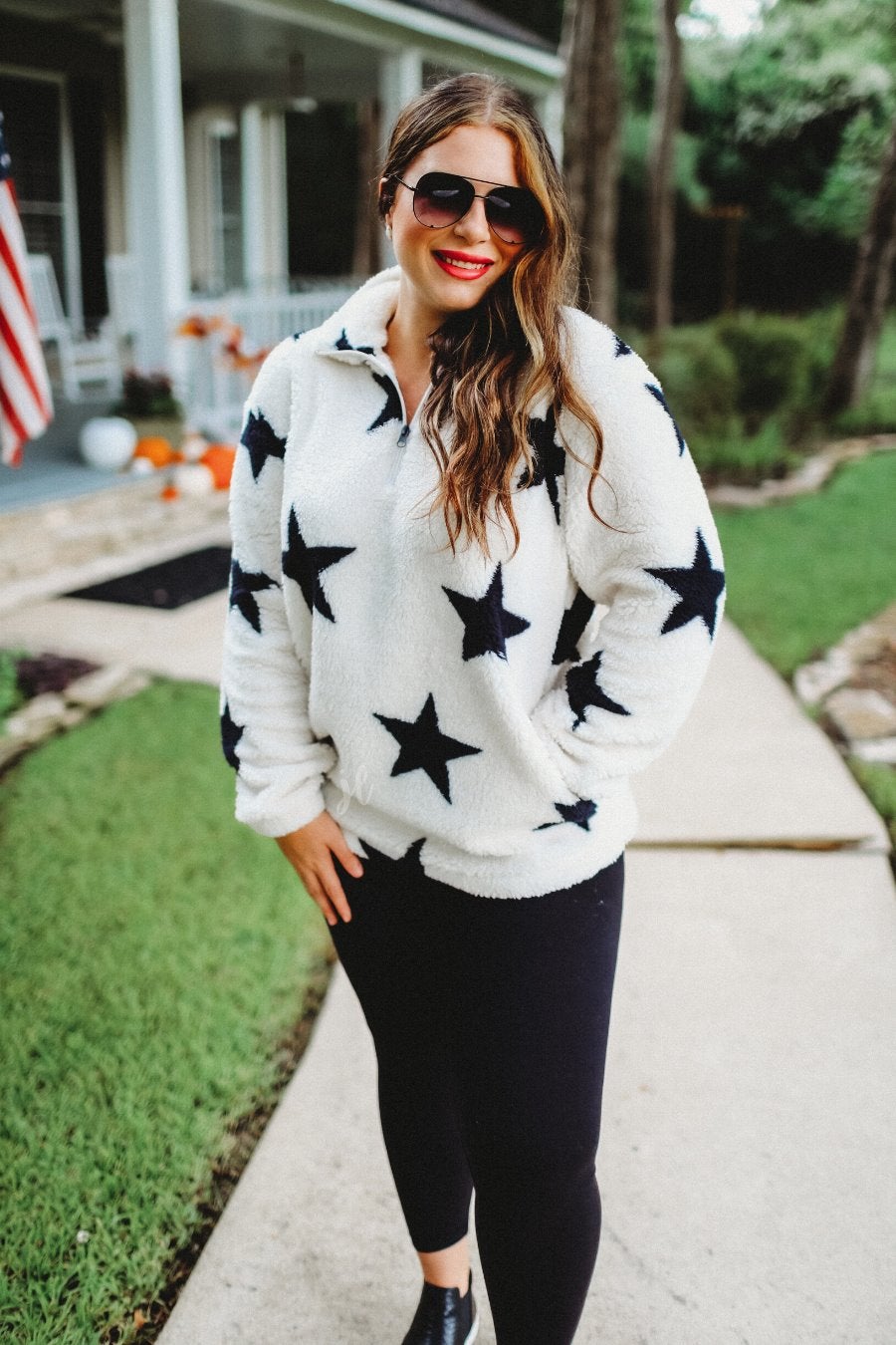 a long-sleeve fluffy pullover with a quarter zip, convenient front pockets, and a foldable collar on a white fabric with a black star pattern