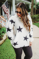 a long-sleeve fluffy pullover with a quarter zip, convenient front pockets, and a foldable collar on a white fabric with a black star pattern