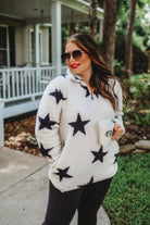 a long-sleeve fluffy pullover with a quarter zip, convenient front pockets, and a foldable collar on a white fabric with a black star pattern