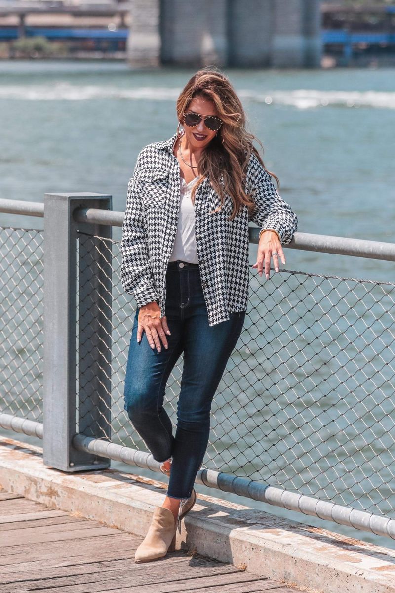 long sleeve drop shoulder shacket with button closures, a button-down front, a collared neckline, chest pockets, and back detailing on a black and white houndstooth print