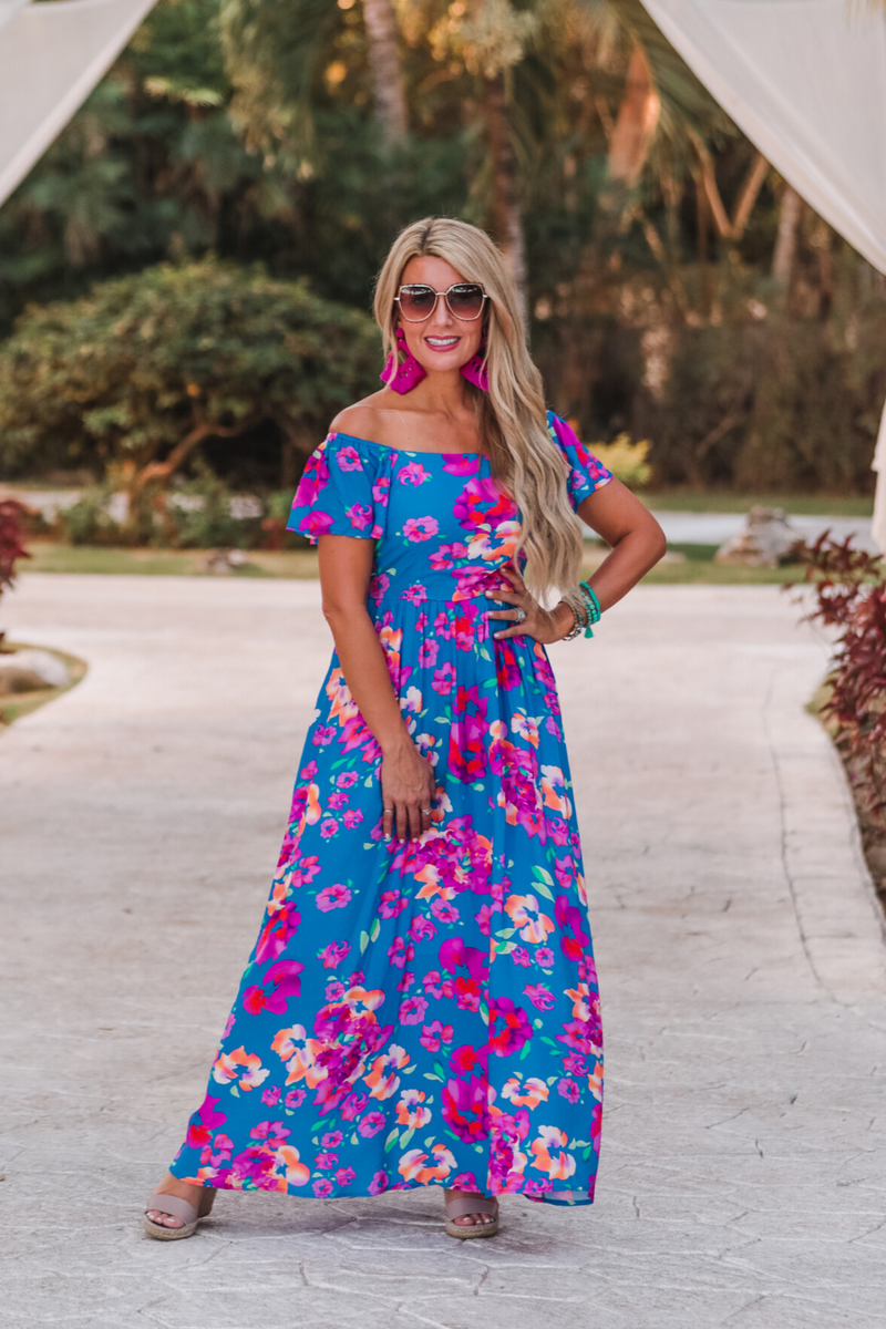 an off-the-shoulder floral dress made of lightweight material with ruffle sleeves, a stretchy smocked back, and interior lining in blue