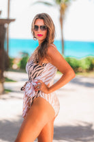 a one-piece swimsuit made of stretchy material with a scoop back, chunky straps, a versatile accent tie, and removable padding on a neutral color block animal print pattern fabric