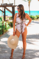 a one-piece swimsuit made of stretchy material with a scoop back, chunky straps, a versatile accent tie, and removable padding on a neutral color block animal print pattern fabric