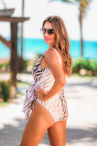 a one-piece swimsuit made of stretchy material with a scoop back, chunky straps, a versatile accent tie, and removable padding on a neutral color block animal print pattern fabric