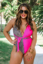 one-piece swimsuit made of lightweight stretchy material with a plunging v-cut neckline, wide shoulder straps that twist across the open back, a flattering figure-hugging silhouette that ends in cheeky fit bottoms, and removable pads on a leopard/hot pink two-tone color block fabric