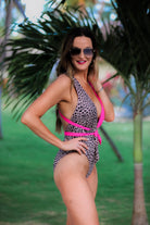 one-piece swimsuit made of lightweight stretchy material with a plunging v-cut neckline, wide shoulder straps that twist across the open back, a flattering figure-hugging silhouette that ends in cheeky fit bottoms, and removable pads on a leopard/hot pink two-tone color block fabric