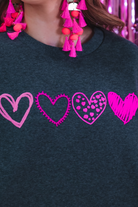 a charcoal long-sleeve sweatshirt with a fuzzy inside, sewn-on pink chenille heart patches, a relaxed drop-shoulder fit, and ribbed detailing on the classic crew neckline, cuffs, and hemline