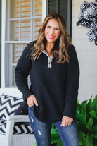 a long-sleeve pullover with a quilted pattern, gold button details, a foldable collar, a round hem, and matching plaid elbow patch and quarter button-up neckline