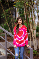 a red lightweight long-sleeve knit top with a bold heart motif layered over a vibrant tie-dye pattern, a flattering scoop neckline, and a streamlined silhouette that finished with a straight hem