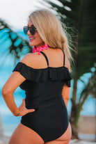 one-piece swimsuit made of stretchy material with a mix of solid black and sheer polka dot fabric, removable padding, ruffle neckline, adjustable spaghetti straps, and chunky shoulder straps that can be worn on or off the shoulder