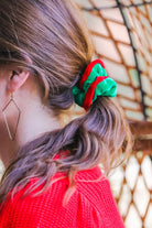 a plush velvet scrunchie in a rich nostalgic colorway (classic green with red trim) with contrasting trim and comfortable elastic