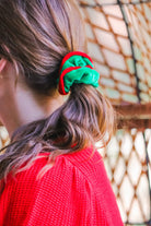 a plush velvet scrunchie in a rich nostalgic colorway (classic green with red trim) with contrasting trim and comfortable elastic