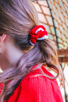 a plush velvet scrunchie in a rich nostalgic colorway (bold red with white trim) with contrasting trim and comfortable elastic