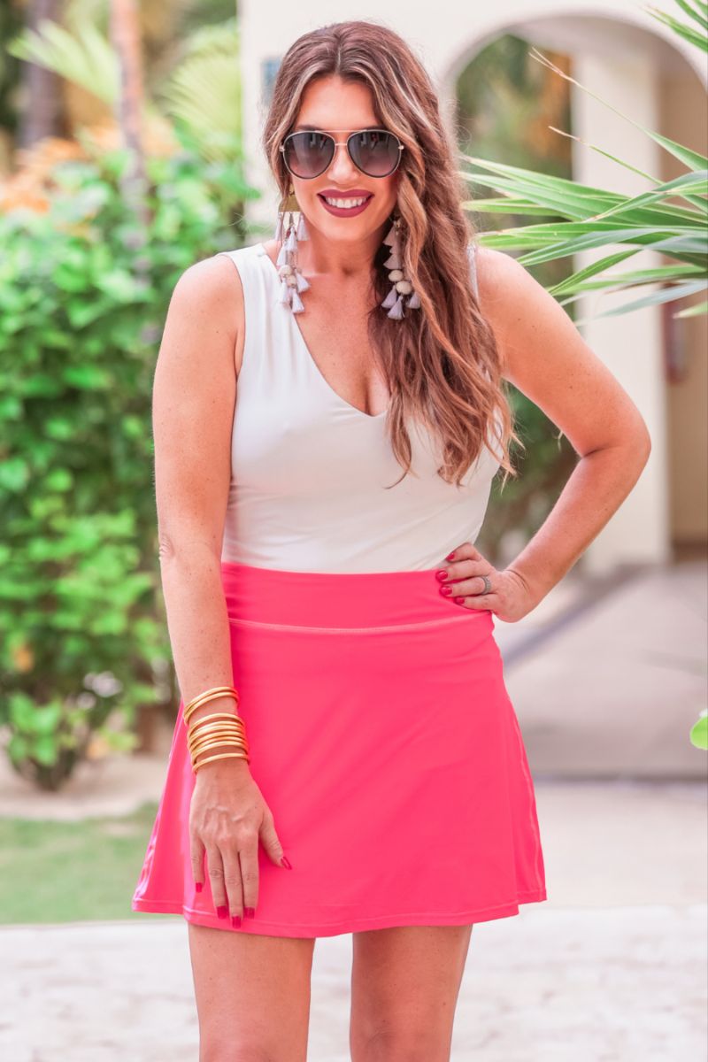 a slimming true to size solid pink skort with built-in shorts, interior side pockets, and a pleated back