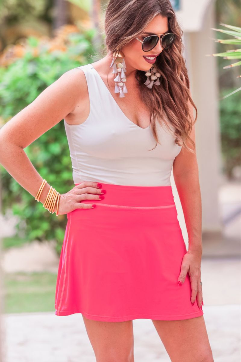 a slimming true to size solid pink skort with built-in shorts, interior side pockets, and a pleated back