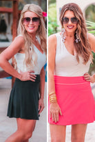 a slimming true to size solid color skort with built-in shorts, interior side pockets, and a pleated back in black and pink