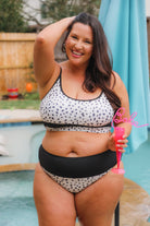 two-piece swimsuit made of lightweight four-way stretchy material and subtle ribbed texturing on a neutral leopard print with a bralette-style top, adjustable spaghetti straps, removable padding, a black band, and flattering form-fitting silhouette paired with high waistline bottoms with a black solid band for added tummy control