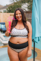 two-piece swimsuit made of lightweight four-way stretchy material and subtle ribbed texturing on a neutral leopard print with a bralette-style top, adjustable spaghetti straps, removable padding, a black band, and flattering form-fitting silhouette paired with high waistline bottoms with a black solid band for added tummy control